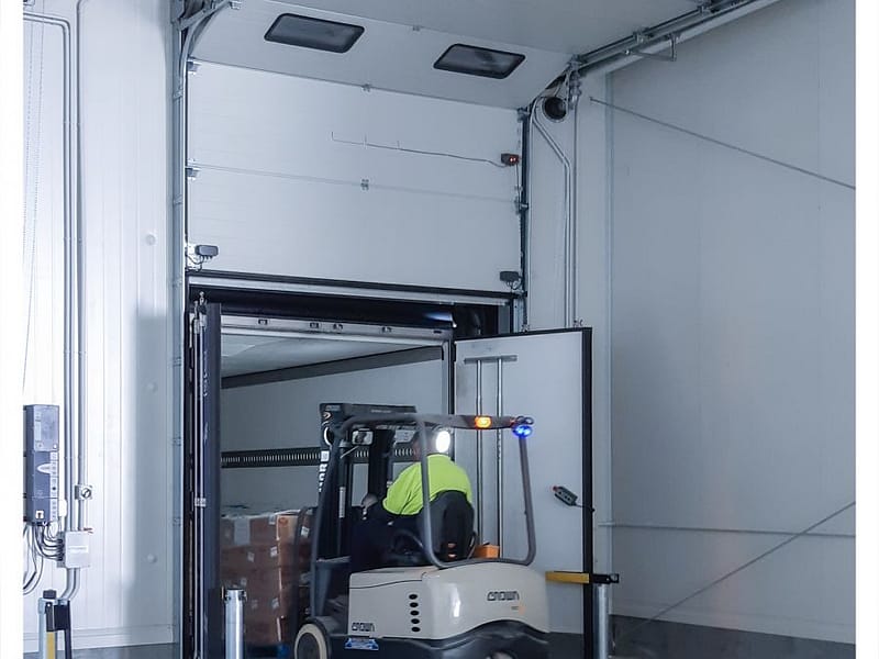 Forklift entering a truck through a DOBO dock system with a sectional door.